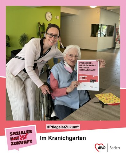 Bewohnerin im Rollstuhl mit AWO‑Mitarbeiterin im Seniorenzentrum Im Kranichgarten zeigt Plakat zum Tag der Pflegenden