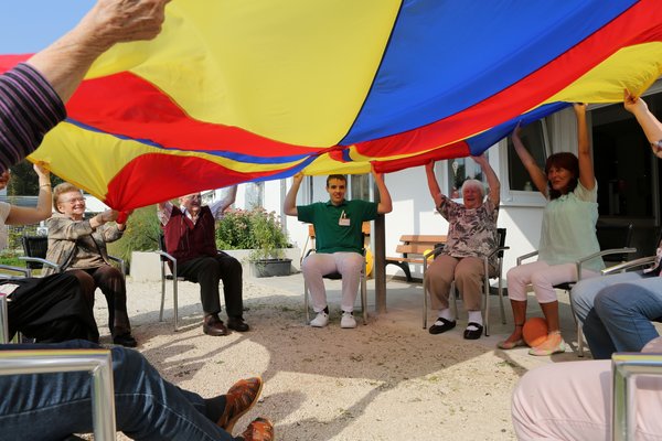 Alltagsbegleiterin und Senioren mit Gymnastiktuch